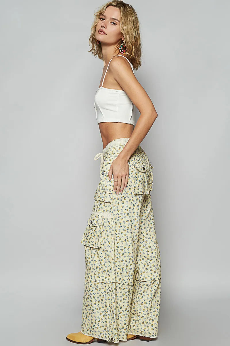 Woman wearing floral wide leg pants with multiple pockets paired with a white crop top and colorful earrings