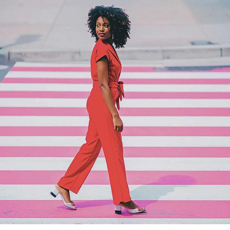 Woman wearing a stylish red lightweight jumpsuits women crosswalk walking outdoors