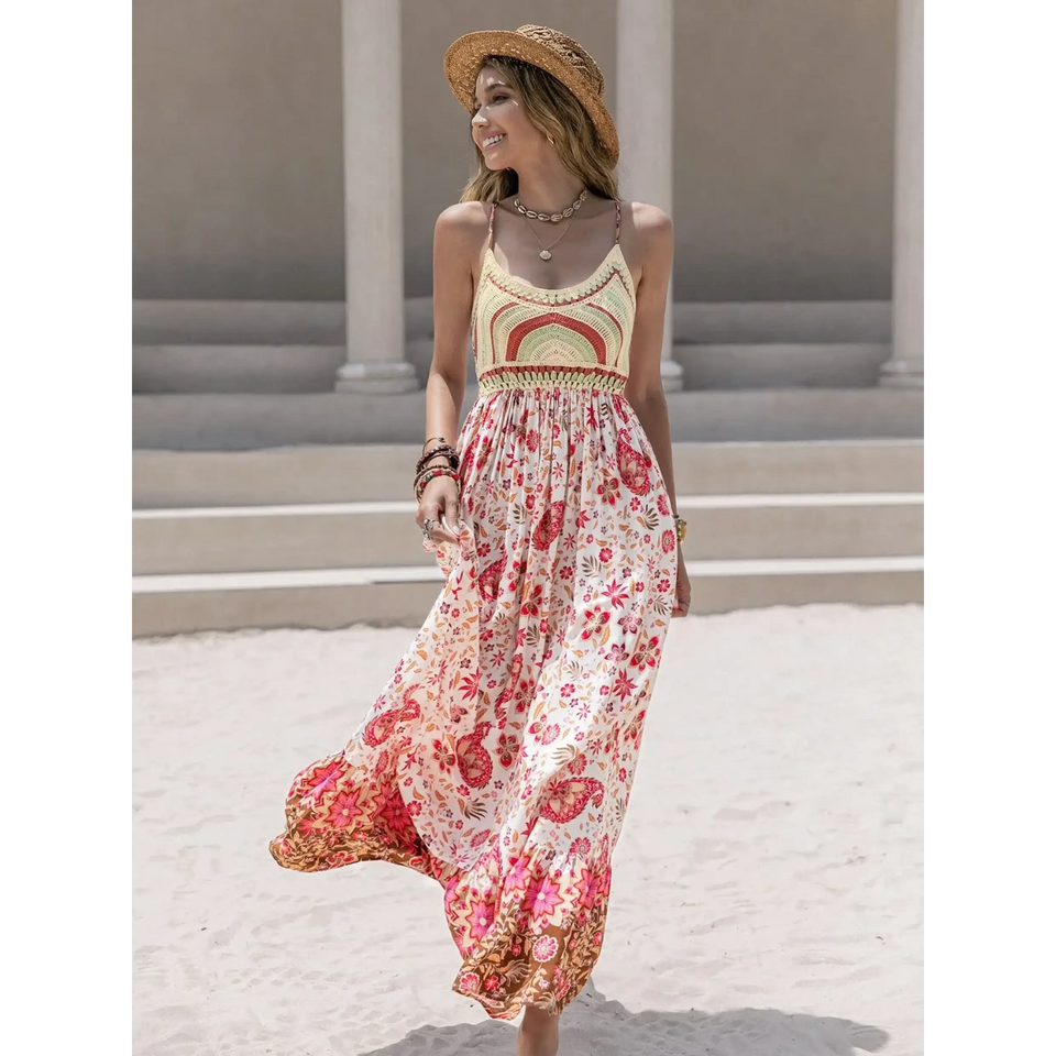 Woman wearing one of the best beach maxi dresses with floral print and straw hat on sandy beach