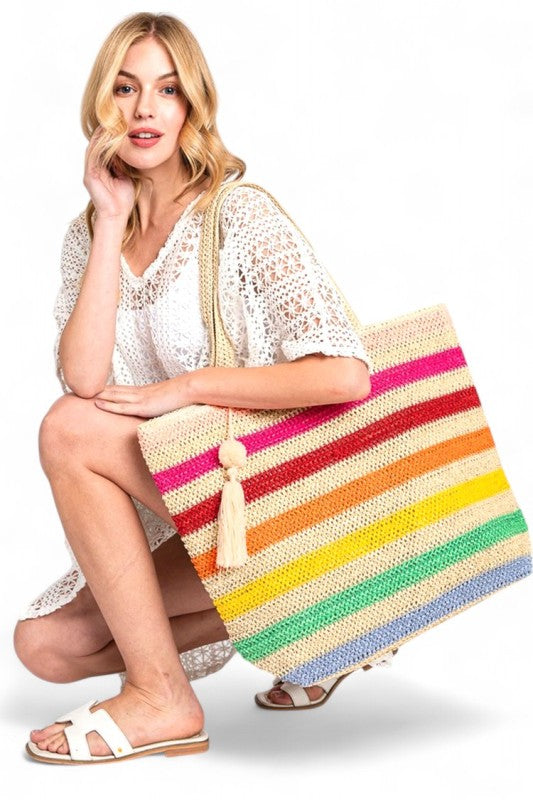 Woman holding large striped beach bag for women with colorful horizontal stripes and tassel detail