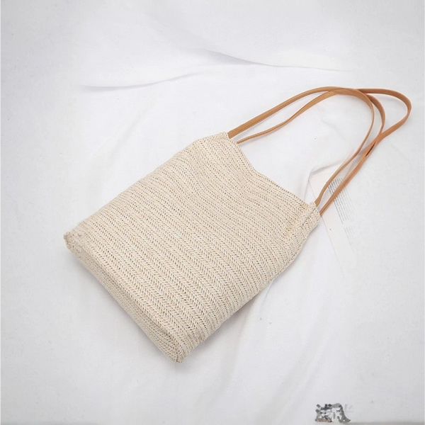 Stylish straw tote with brown straps, perfect for beach days and summer adventures