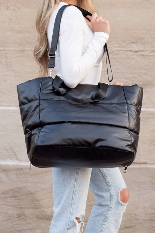 Black large lightweight puffer weekends bag carried by a woman with adjustable shoulder strap