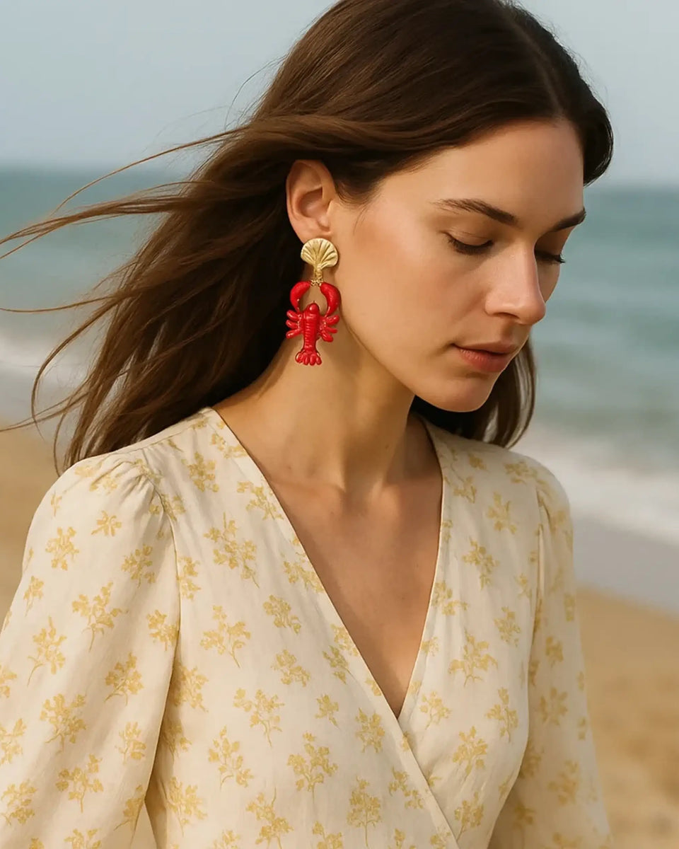 Trendsi Lobster Drop Earrings Resort in red worn by woman at the beach with beige floral dress