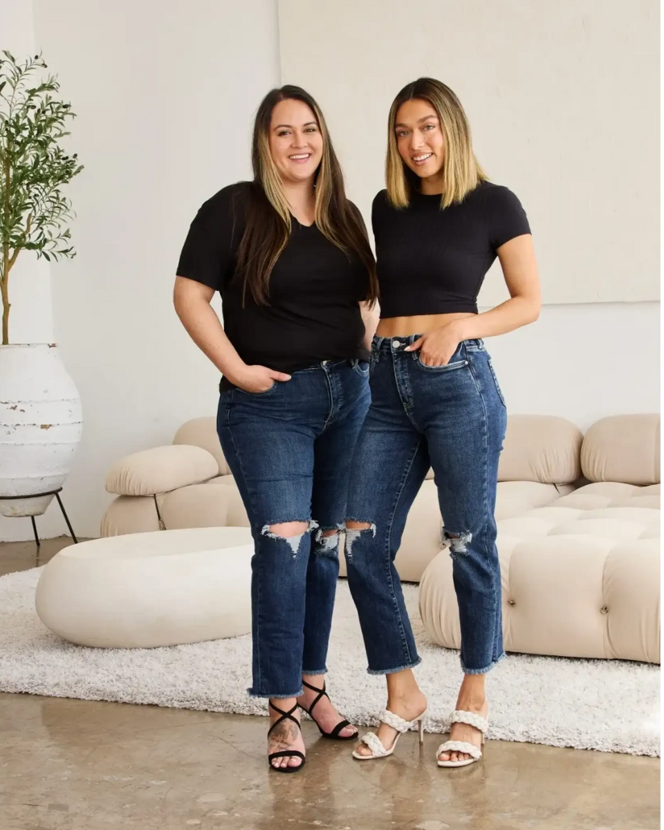 Two women wearing Trendsi tummy control high waist jeans with ripped knees and black tops in modern living room