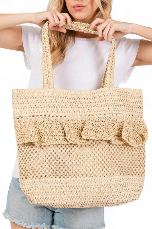 Artini Accessories uniqe ruffle straw bag in natural beige held by a woman wearing white shirt and denim shorts