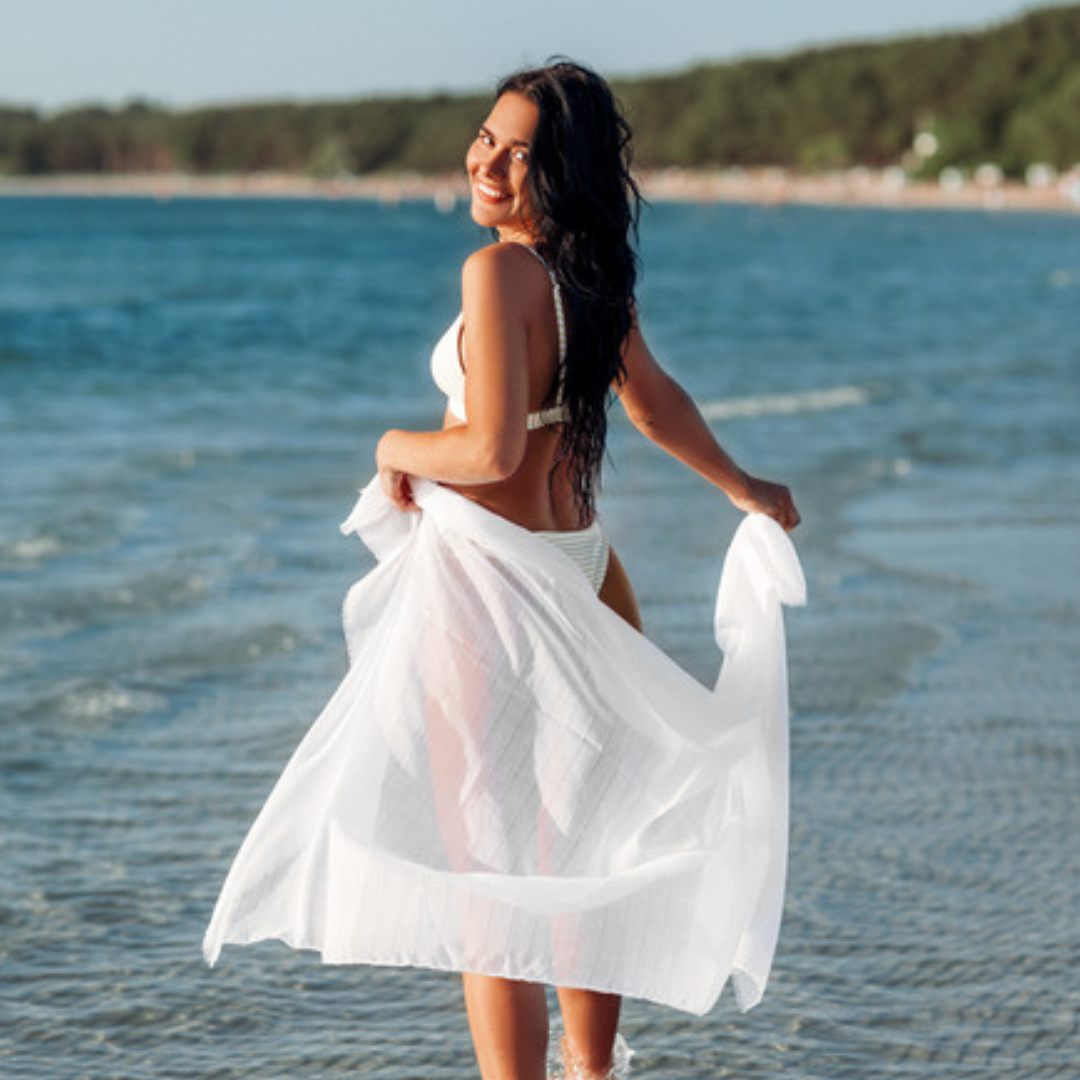 Woman wearing white swimsuit cover ups trending 2025 sheer beach wrap at the shore