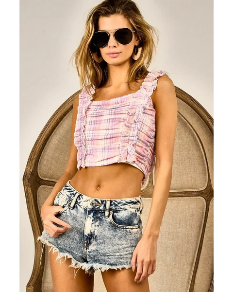 Woman wearing summer resort wear tops in pink plaid with ruffles paired with denim shorts and sunglasses