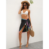 Beach Babes black coverup wrap with colorful trim worn over white bikini with woman holding straw bag