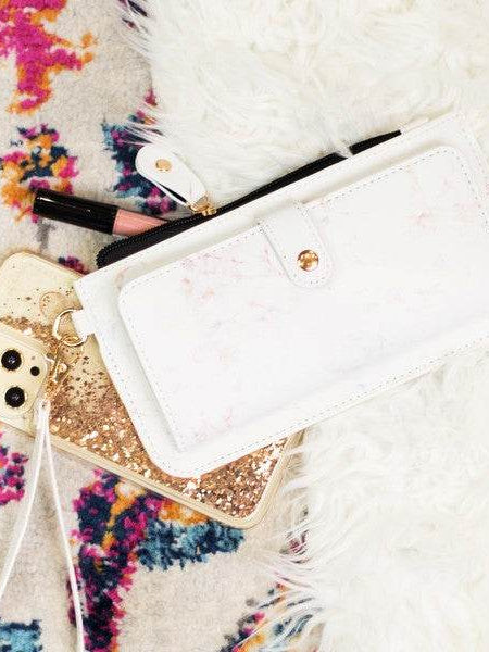 Babe Beachwear white cruise wristlet wallet for women placed on colorful rug with gold phone and makeup