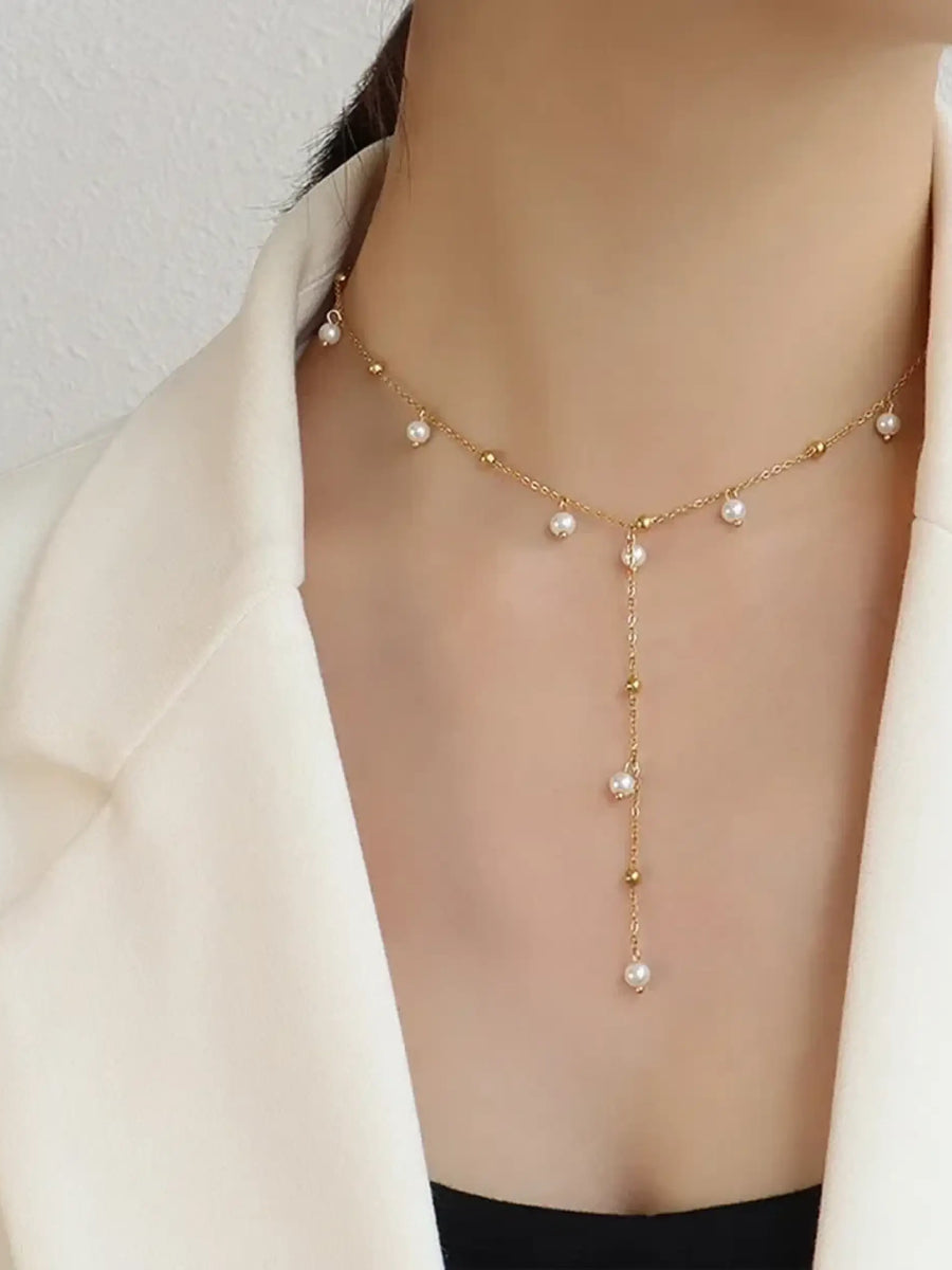 Delicate 18K gold plated pearl necklace with hanging pearl details worn with a white blazer