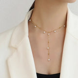 Delicate 18K gold plated pearl necklace with hanging pearl details worn with a white blazer