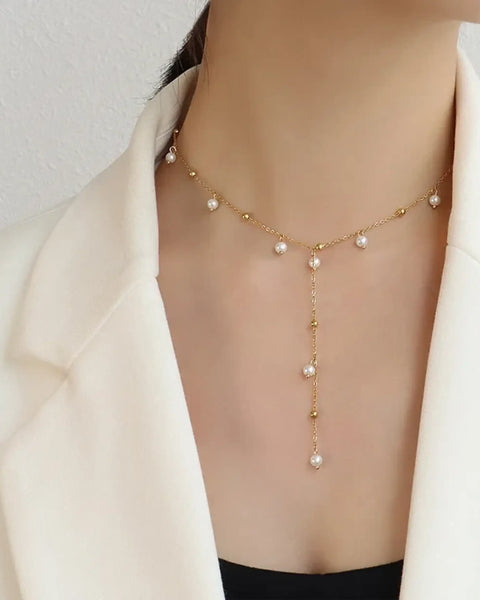 Delicate 18K gold plated pearl necklace with hanging pearl details worn with a white blazer