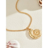 Trendsi 18K gold shell pendant necklace with a detailed spiral shell design on a textured surface