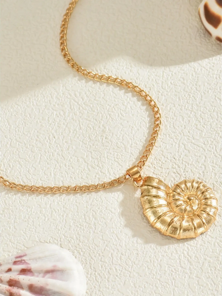 Trendsi 18K gold shell pendant necklace with a detailed spiral shell design on a textured surface