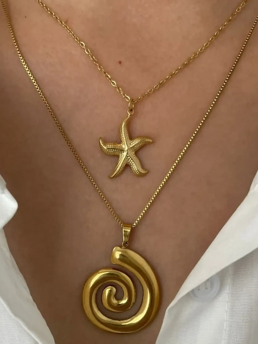 Elegant 18k gold starfish necklace layered with a gold spiral pendant necklace on a model