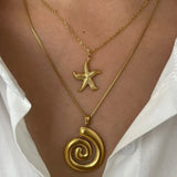 Elegant 18k gold starfish necklace layered with a gold spiral pendant necklace on a model