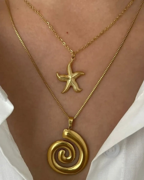 Elegant 18k gold starfish necklace layered with a gold spiral pendant necklace on a model