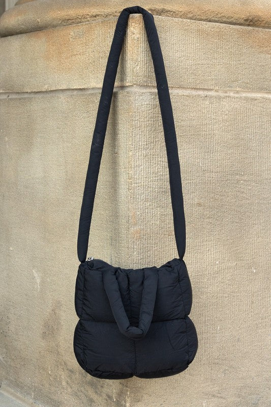 Black Babe Beachwear Jacie Puffer Mini Tote bag with long strap hanging on stone wall