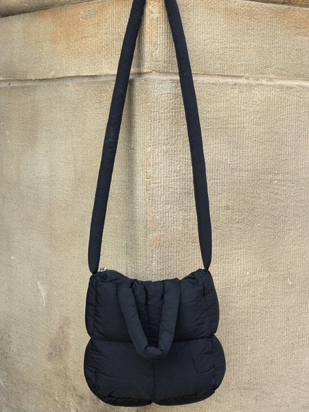 Black Babe Beachwear Jacie Puffer Mini Tote bag with long strap hanging on stone wall