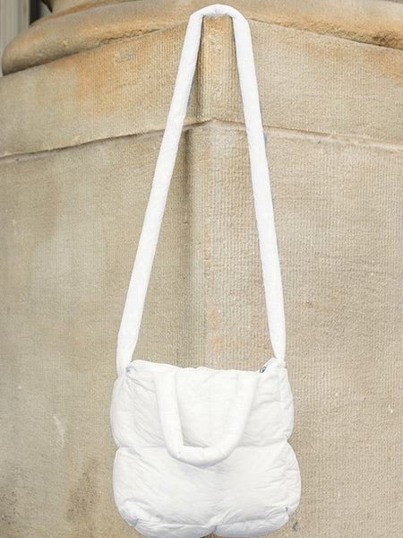 Babe Beachwaer Jacie Puffer Mini Tote white quilted bag with long strap hanging on textured wall