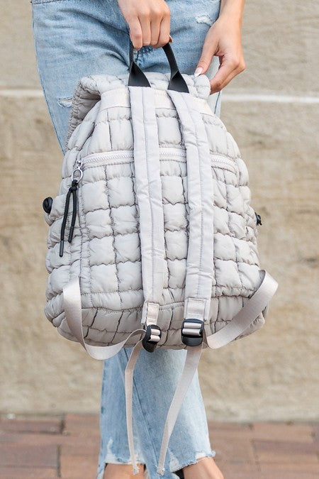 Babe Beachwaer Puffer Backpack Lightweight in light gray held by person wearing ripped jeans