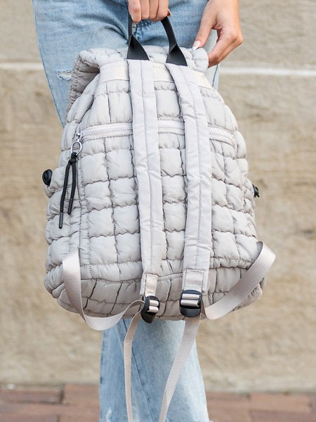 Babe Beachwaer Puffer Backpack Lightweight in light gray held by person wearing ripped jeans