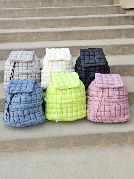 Babe Beachwear Puffer Backpack Lightweight collection in gray white black blue green and pink colors on stone steps