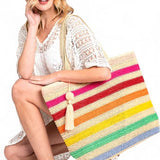 Woman holding large striped beach bag for women with colorful horizontal stripes and tassel detail