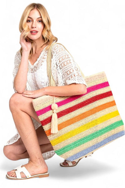 Woman holding large striped beach bag for women with colorful horizontal stripes and tassel detail