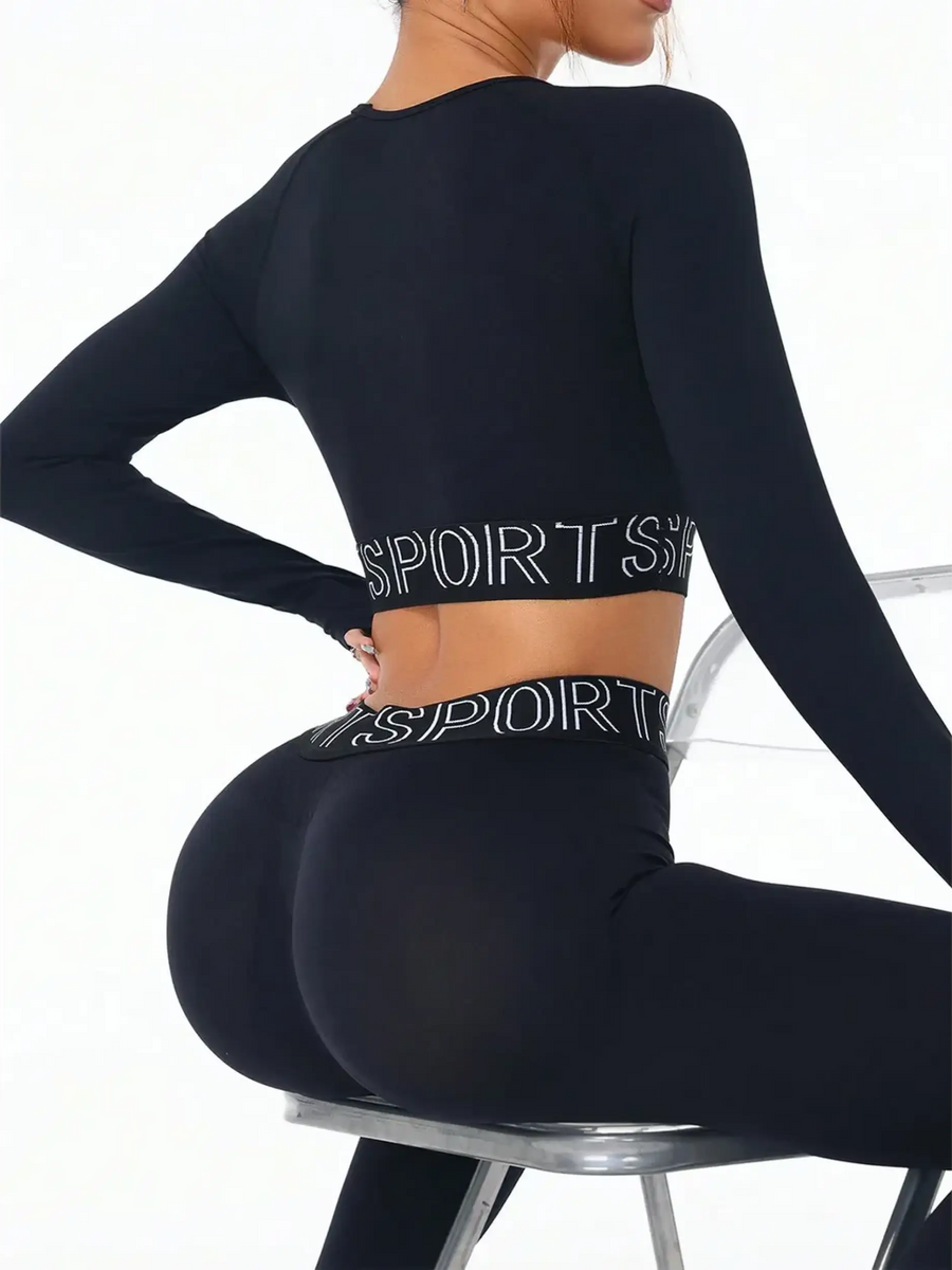 Trendsi branded leggings and tank outfit in black with long sleeves and sporty waistband sitting on a chair
