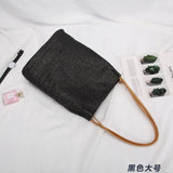 Black woven tote bag with brown handles perfect for stylish straw totes and beach days