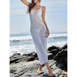 Woman wearing a delicate sheer swimsuit cover up by Babe Beachwear standing on rocky shore by the ocean