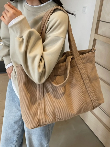Lightweight Ladies duffle bag in beige corduroy fabric carried over shoulder by woman