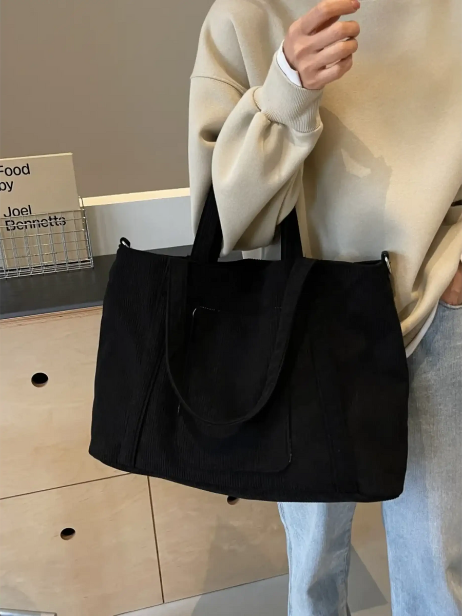 Lightweight ladies duffle bag in black by Babe Beachwaer held by a person wearing beige sweater and blue jeans