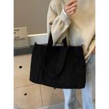 Lightweight ladies duffle bag in black by Babe Beachwaer held by a person wearing beige sweater and blue jeans