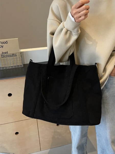 Lightweight ladies duffle bag in black by Babe Beachwaer held by a person wearing beige sweater and blue jeans