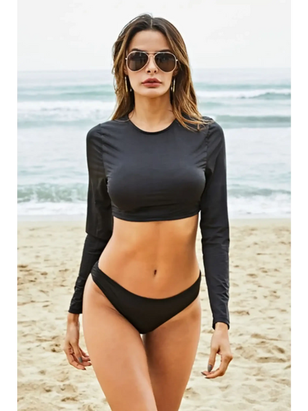 Beach Babes black long sleeve two piece swimsuit worn by model on sandy beach with ocean background