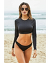 Beach Babes black long sleeve two piece swimsuit worn by model on sandy beach with ocean background