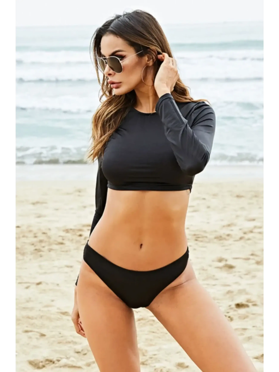 Beach Babes black long sleeve two piece swimsuit worn by woman posing on sandy beach
