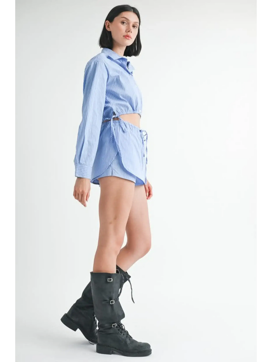 Woman wearing blue and white cotton beach top with long sleeves and side tie detail paired with black boots