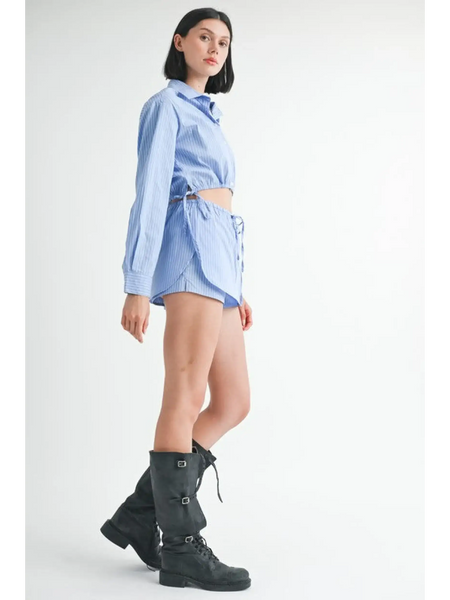 Woman wearing blue and white cotton beach top with long sleeves and side tie detail paired with black boots