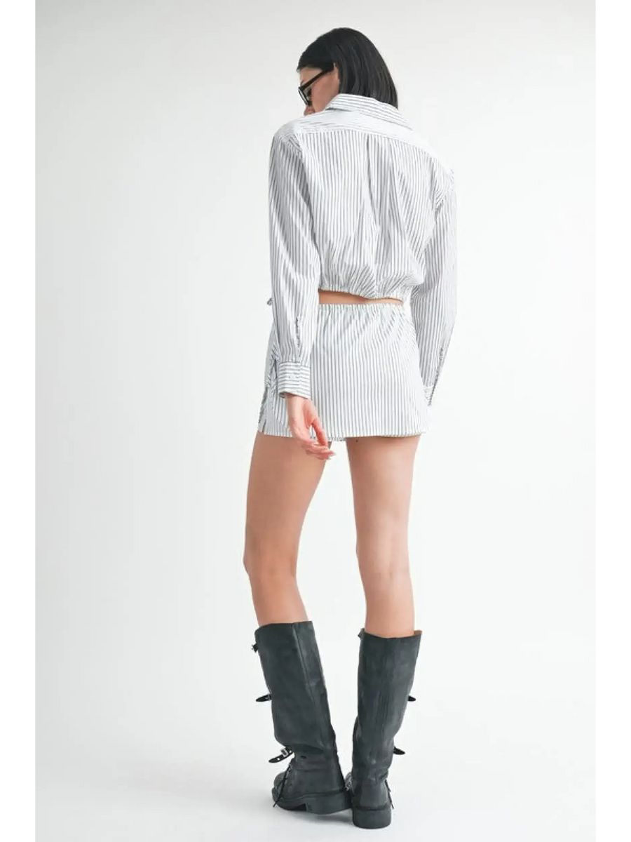 Back view of woman wearing blue and white cotton beach top with matching shorts and black boots