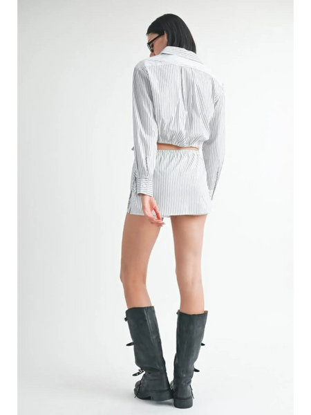 Back view of woman wearing blue and white cotton beach top with matching shorts and black boots