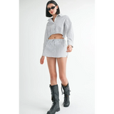 Woman wearing a blue and white cotton beach top paired with matching shorts and black boots