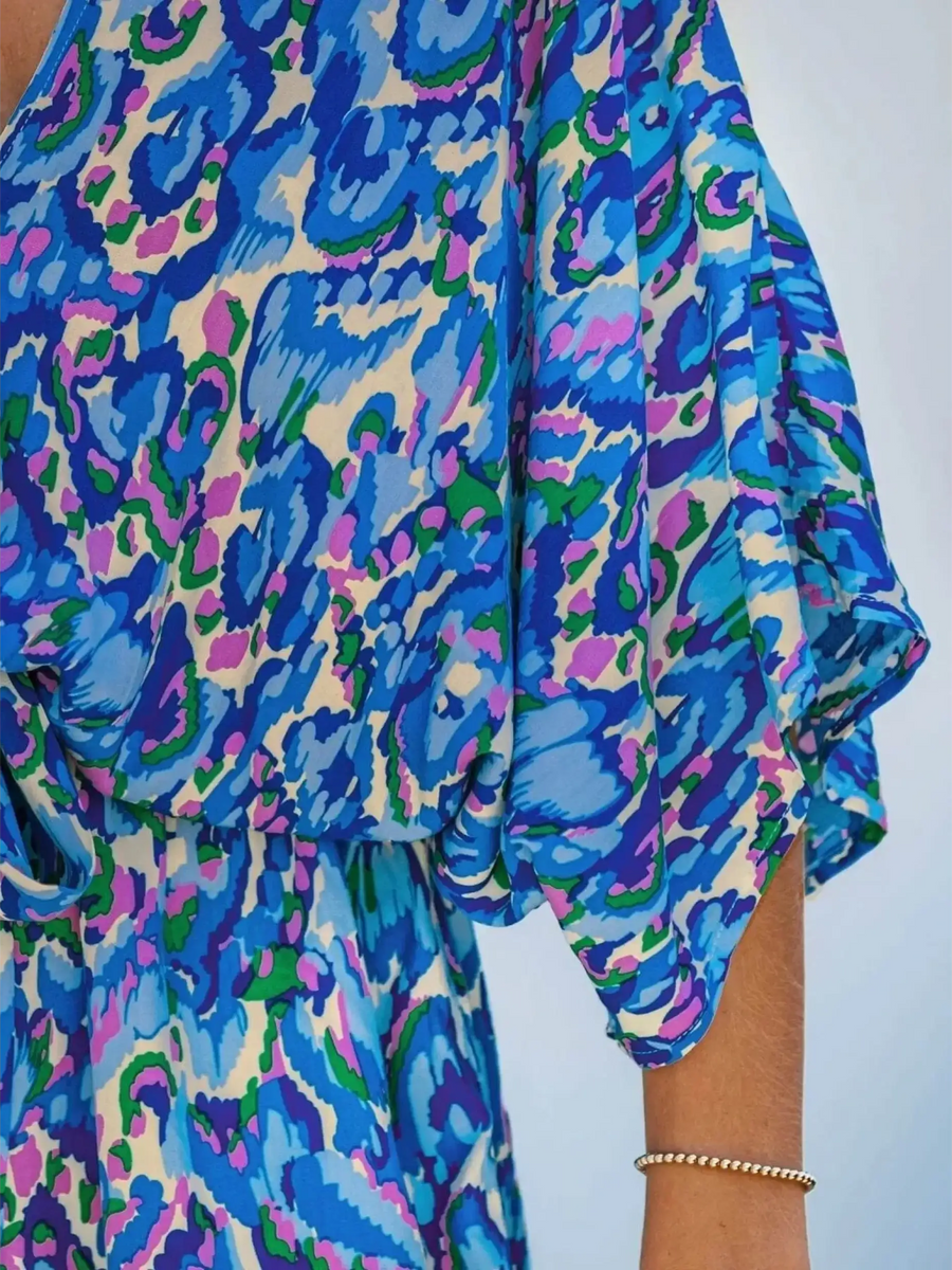 Babe Beachwaer blue batwing romper for travel with vibrant abstract print and flowing sleeve detail