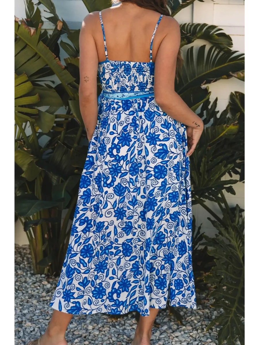 woman wearing blue floral maxi dress with a back view with spaghetti straps and fitted waist midi dress