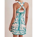 Back view of a blue mini dress by Trendsi with cross back straps and floral pattern