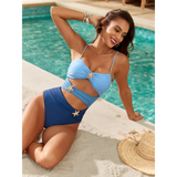 Trendsi blue one piece swimsuit with cutouts modeled by woman sitting by poolside on sand