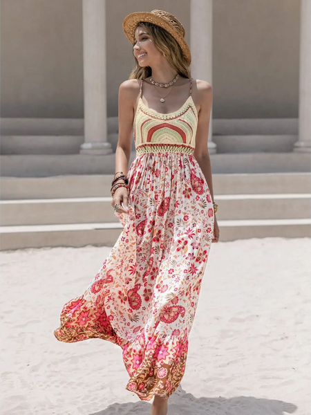 Woman wearing a crochet boho maxi dress with floral patterns and a straw hat on a sandy beach