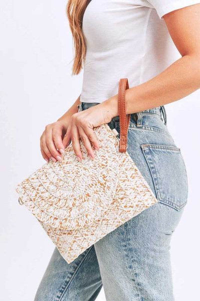 Babe Beachwaer boho ivory clutch bag with woven texture and brown wrist strap held by woman in white top and jeans